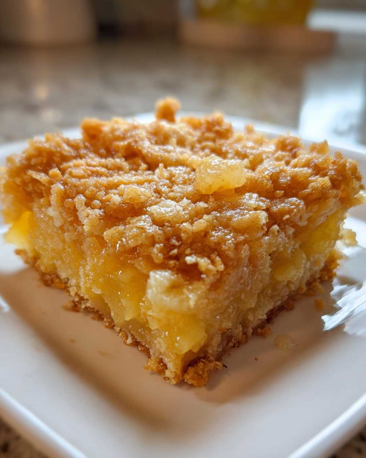 Close-up of a square serving of Paula Deen Pineapple Casserole showing the gooey pineapple filling and crunchy brown sugar topping.