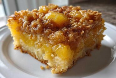 Close-up of a moist slice of Paula Deen Pineapple Casserole featuring chunks of pineapple and a brown sugar crumb topping.