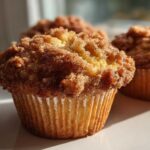 A close-up of a moist Pineapple Muffins With Crumb Topping featuring a thick, sugary cinnamon streusel topping.
