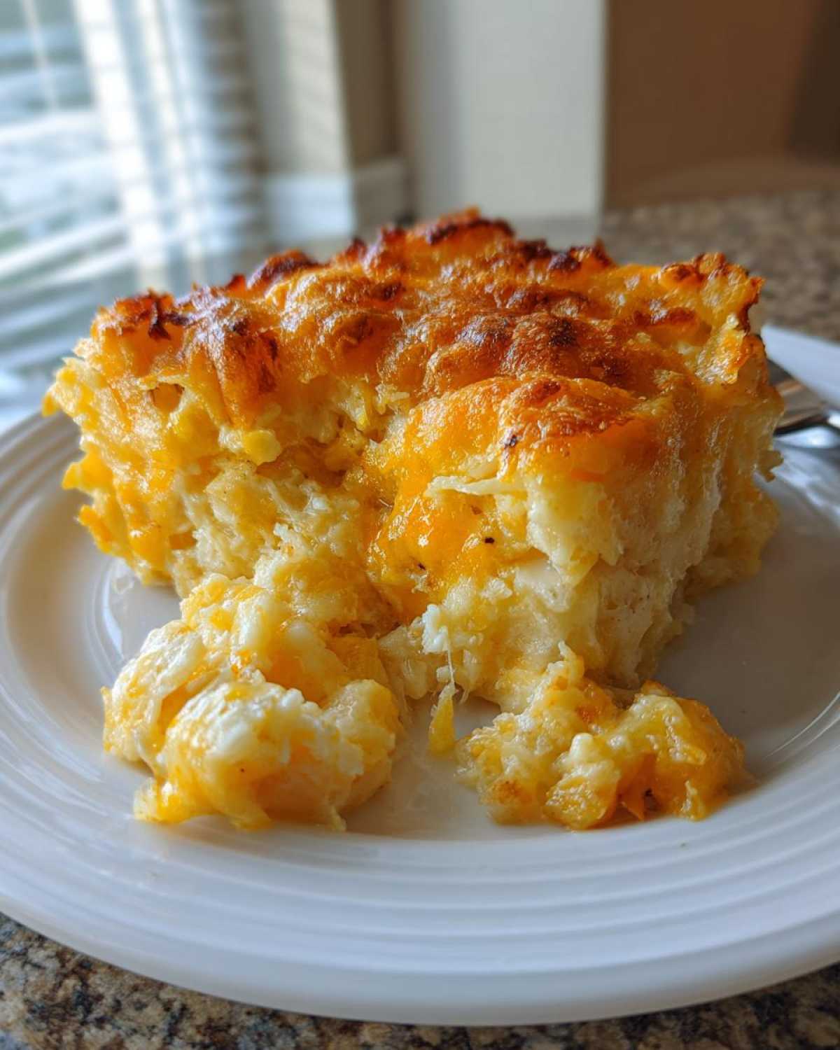 A close-up serving of creamy, cheesy funeral potatoes recipe with a golden-brown, bubbly top.