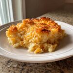 A square serving of cheesy, baked funeral potatoes recipe with a golden-brown, crispy top.