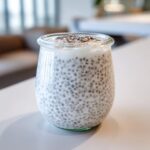 Close-up of creamy chia seed pudding made with milk in a small glass jar, ready to eat.