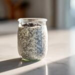 A single serving of creamy chia seed pudding prepared in a small glass jar, sitting on a bright countertop.