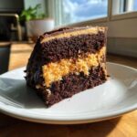 A decadent slice of german chocolate cake featuring dark chocolate layers and a thick, toasted coconut pecan filling.
