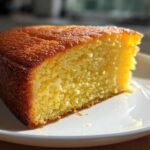 Close-up of a moist slice of golden olive oil cake showing its fine crumb texture, served on a white plate.