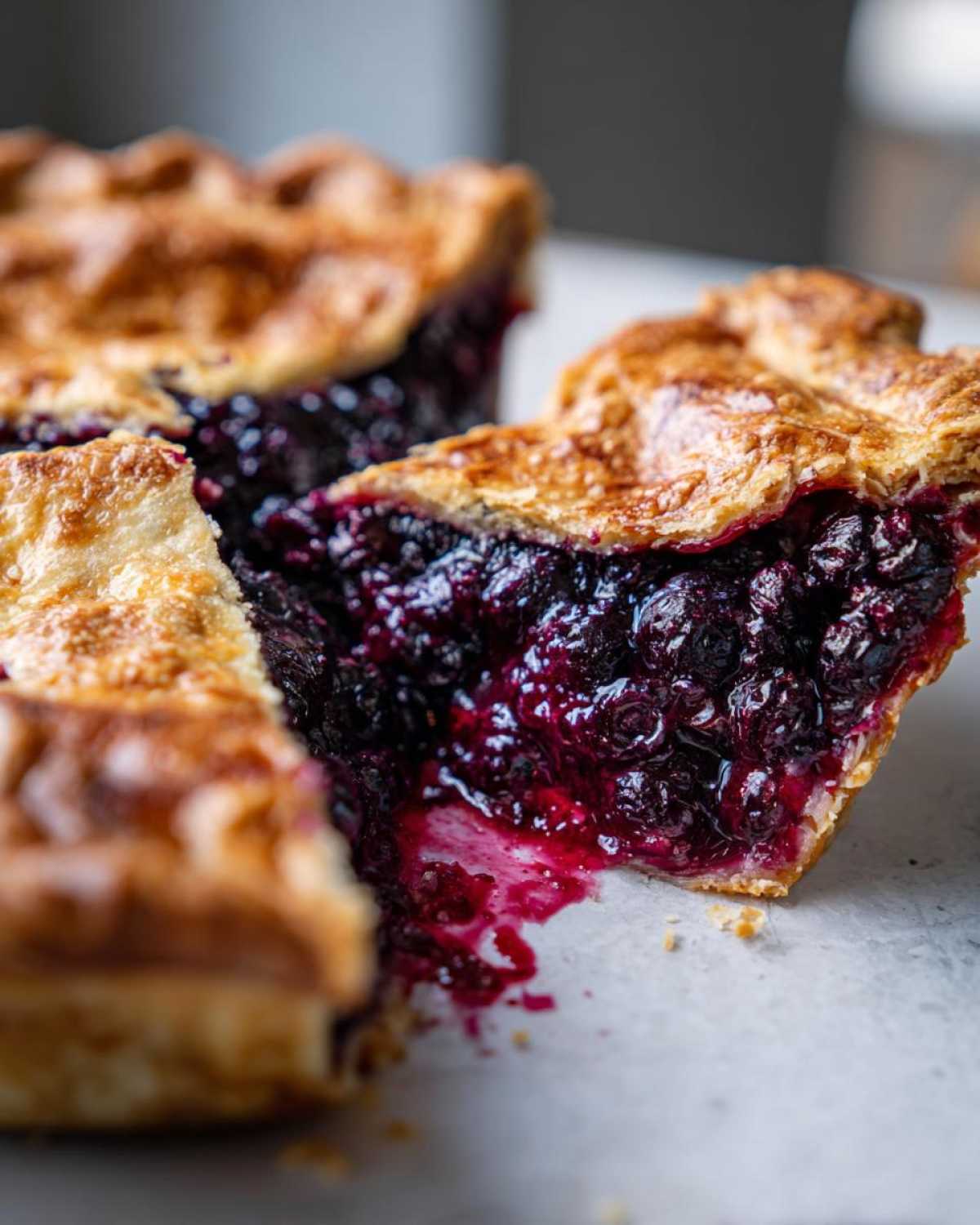 Close-up of a juicy blueberry berry pie showing the rich purple filling and golden lattice crust.