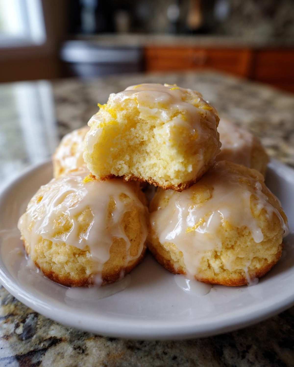 Close-up of soft Italian ricotta cookies stacked on a plate, drizzled with white glaze and lemon zest.
