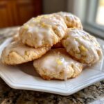 A stack of soft italian ricotta cookies topped with thick white lemon glaze and bright yellow zest.