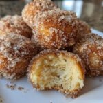 A pile of Soft & Sweet Cinnamon Sugar Biscuit Bites coated heavily in sparkling cinnamon sugar, one is broken open.