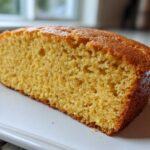 Close-up view of a thick slice of golden sourdough cornbread showing its moist, crumbly texture.