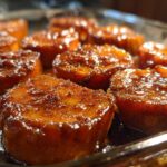 Close-up, low-angle shot of thick-cut, glazed southern candied yams bubbling in a baking dish.