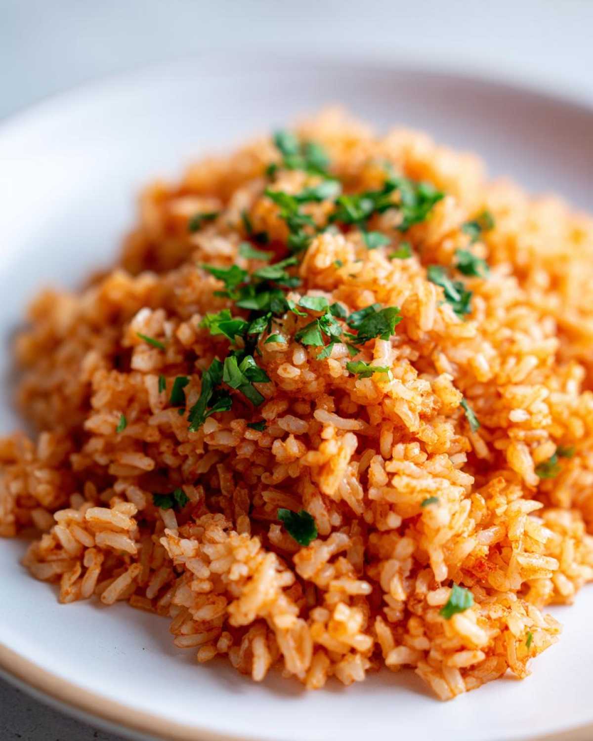 Close-up of a serving of vibrant orange Spanish rice topped with chopped fresh parsley.