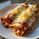 Two baked easy chicken enchiladas covered in melted red sauce and golden cheese on a white plate.