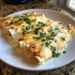 Three delicious white chicken enchiladas covered in melted white and cheddar cheese and fresh parsley.