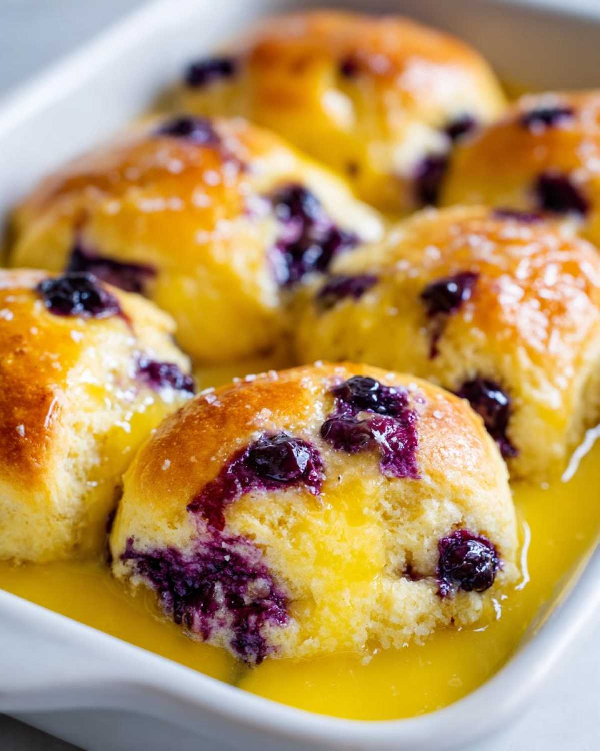 Close-up of freshly baked Blueberry Butter Swim Biscuits soaking in melted butter.