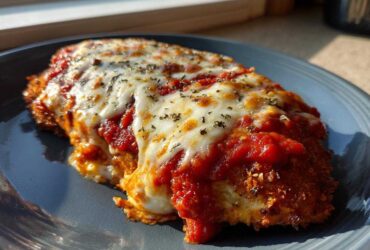 A close-up of a freshly baked Chicken Parmesan cutlet covered in rich tomato sauce and melted mozzarella cheese.