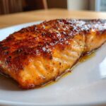 Close-up of a perfectly baked salmon fillet with a caramelized, seasoned crust, ready to eat.