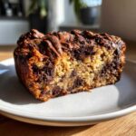 Close-up of a thick slice of Delicious Brookie Baked Oats Recipe, showing a marbled texture with chocolate chips and a melted chocolate drizzle.