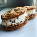 Two homemade Chocolate Chip Ice Cream Sandwiches made with soft chocolate chip cookies and vanilla ice cream filling.