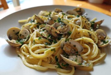 A close-up of a white plate filled with delicious Linguine and Clams tossed in a white wine sauce and fresh parsley.