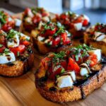 Several pieces of Fresh Caprese Crostini topped with mozzarella, tomatoes, basil, and balsamic glaze on a wooden cutting board.