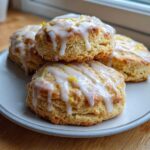 A stack of four freshly baked Lemon Vanilla Scones topped with white glaze and bright yellow lemon zest.