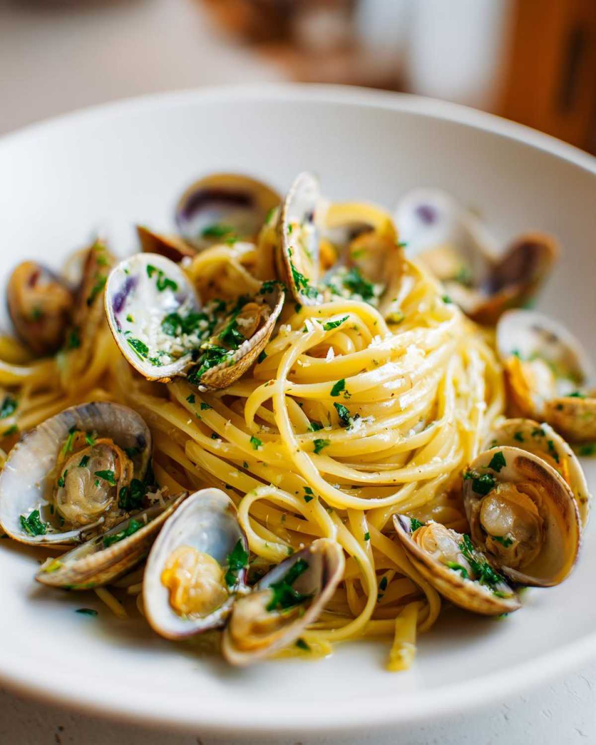 A close-up of a white bowl filled with perfectly cooked Linguine and Clams, garnished with parsley.