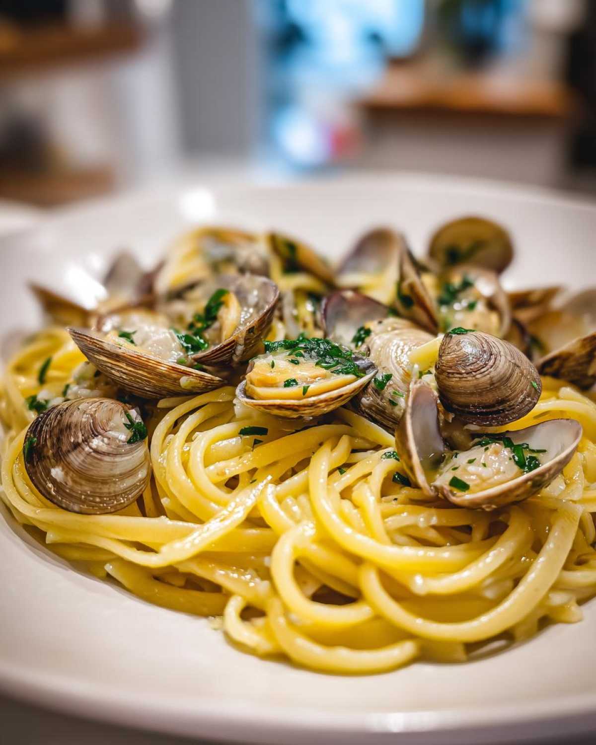A close-up, appetizing shot of Linguine and Clams tossed in a light sauce and garnished with fresh parsley.