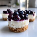A close-up of one of the Little Blueberry Cheesecakes That Make Perfect Sweet Treats, topped with glossy blueberries.