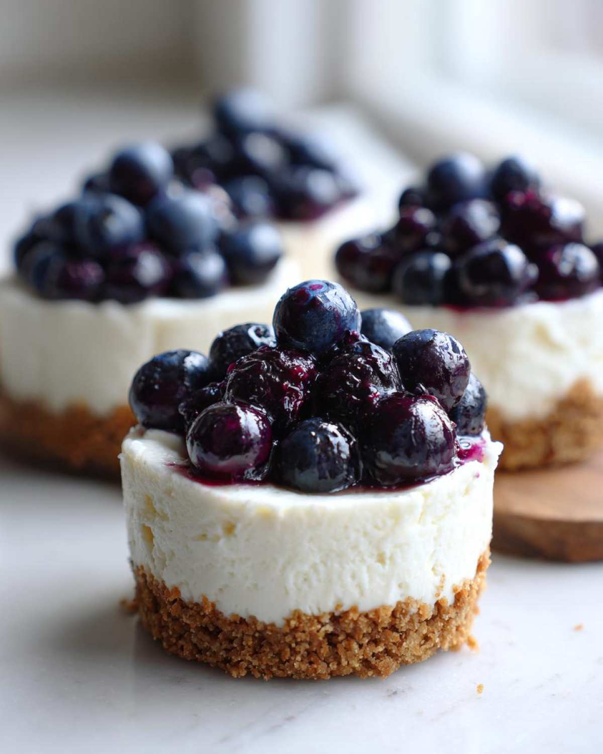 A close-up of one of the Little Blueberry Cheesecakes That Make Perfect Sweet Treats, topped with glossy blueberries.