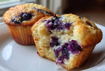Close-up of a Moist and Fluffy Bakery-Style Blueberry Muffin broken open showing the tender crumb and juicy blueberries.
