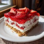 A perfect square slice of No Bake Strawberry Lasagna showing graham cracker crust, creamy filling, and glossy strawberry topping.
