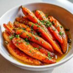 Close-up of whole Roasted Carrots Hot Honey Butter, glistening with glaze and topped with fresh parsley.