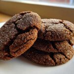 A close-up stack of four dark brown, crinkled Soft & Chewy Molasses Cookies generously coated in sparkling granulated sugar.