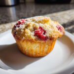 Close-up of a freshly baked Strawberry Shortcake Muffins Recipe Easy 5-Minute snack, topped with visible strawberries and powdered sugar.
