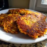 Close-up of golden-brown, crispy Sweet Potato Apple Hashbrowns stacked on a white plate.