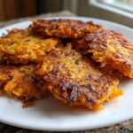 A stack of crispy, golden-brown Sweet Potato Apple Hashbrowns served on a white plate.