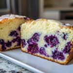Two thick slices of moist Blueberry Cream Cheese Bread Loaf showing rich purple blueberries inside a light yellow crumb.