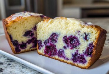 Two thick slices of moist Blueberry Cream Cheese Bread Loaf showing rich purple blueberries inside a light yellow crumb.