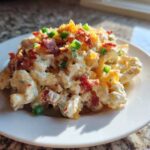 A serving of creamy Chicken Bacon Ranch Pasta Salad topped with crumbled bacon, shredded cheese, and green onions.