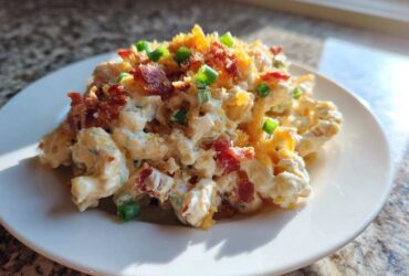 A serving of creamy Chicken Bacon Ranch Pasta Salad topped with crumbled bacon, shredded cheese, and green onions.