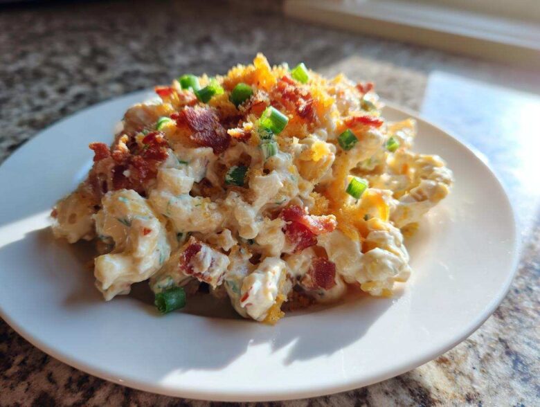 A serving of creamy Chicken Bacon Ranch Pasta Salad topped with crumbled bacon, shredded cheese, and green onions.