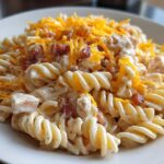 A close-up of creamy Bacon Pasta Salad made with rotini pasta, bacon bits, and topped with shredded cheddar cheese.