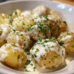 Close-up of tender baby potatoes smothered in creamy garlic sauce and topped with fresh parsley, perfect for Creamy Garlic Sauce Baby Potatoes.