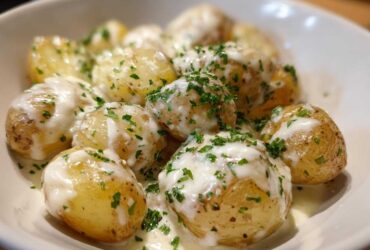 Close-up of tender baby potatoes smothered in creamy garlic sauce and topped with fresh parsley, perfect for Creamy Garlic Sauce Baby Potatoes.