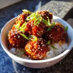 Close-up of saucy Meatball Rice Bowls with Korean Flair, topped with sesame seeds and green onions.