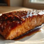Close-up of a perfectly cooked Texas Roadhouse Style Baked Salmon fillet covered in a thick, dark, sweet and savory glaze.